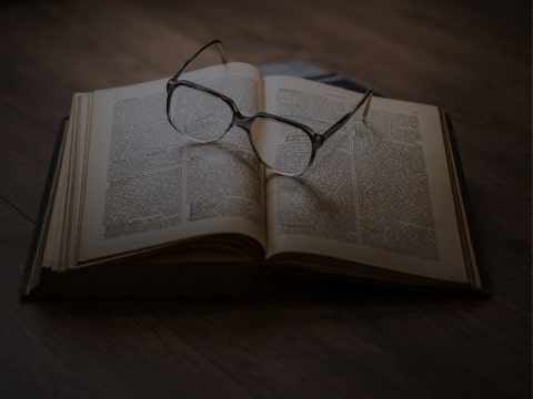 A pair of glasses sitting on top of an open book.